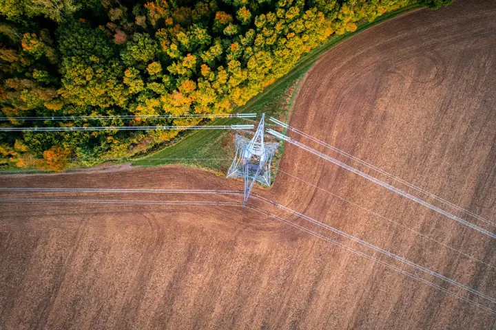 High voltage power line, forest and field from above